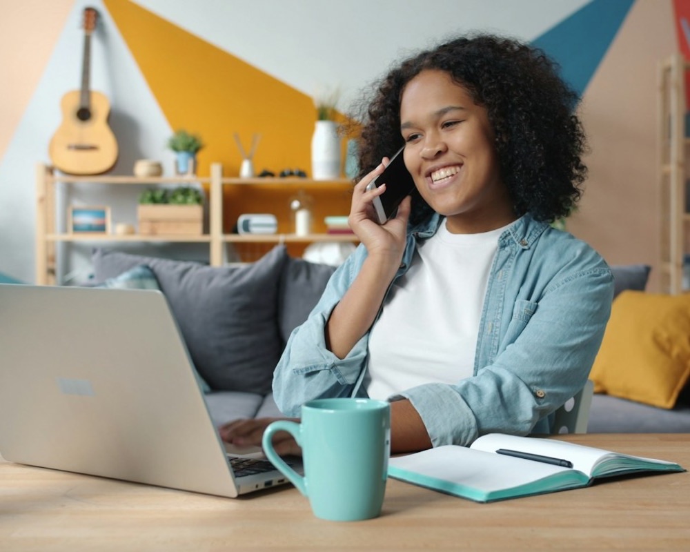 Freelancer smiling on a phone call at her desk at home
