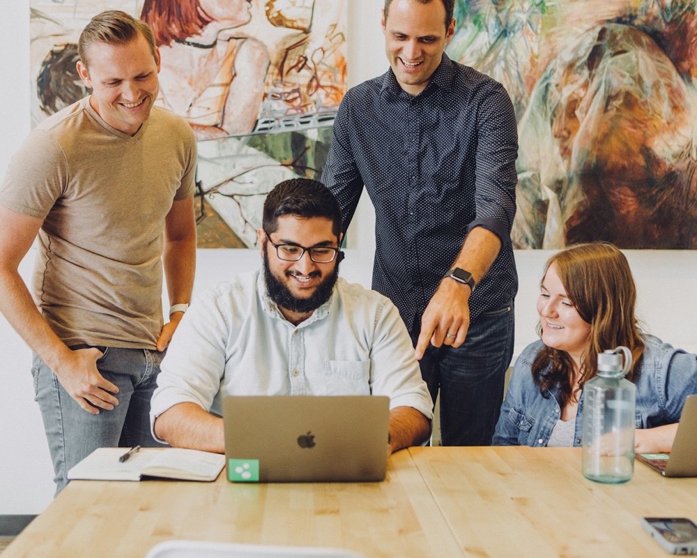 Small team gathered around a laptop, smiling