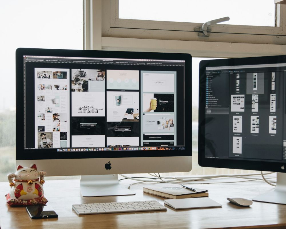 Website page designs open on two computer screens